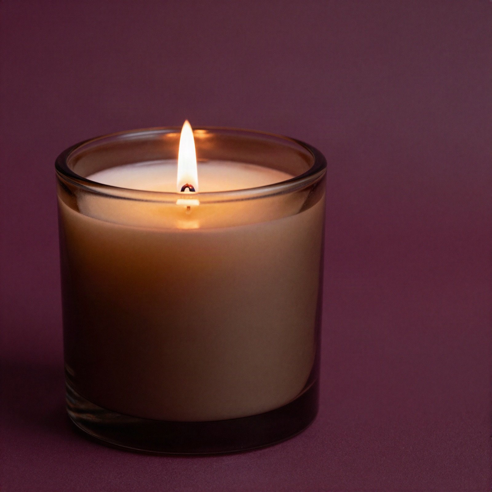 Scented candle in a smoked glass jar on a plum background