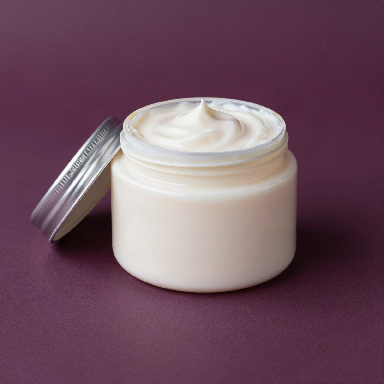Open jar of creamy pearl-white hair mask with its silver lid