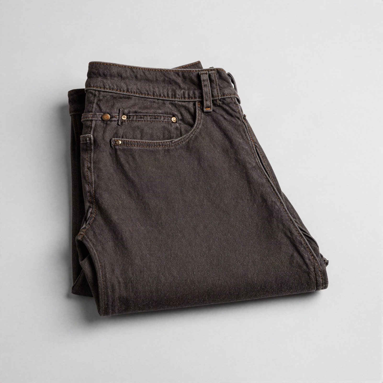 A pair of neatly folded dark brown denim jeans