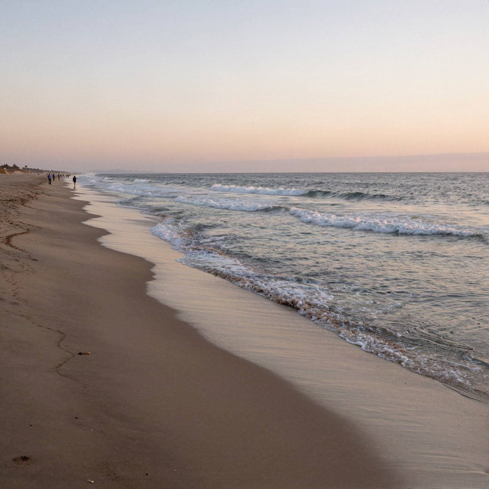 A long sandy ocean beach with gentle waves at sunset