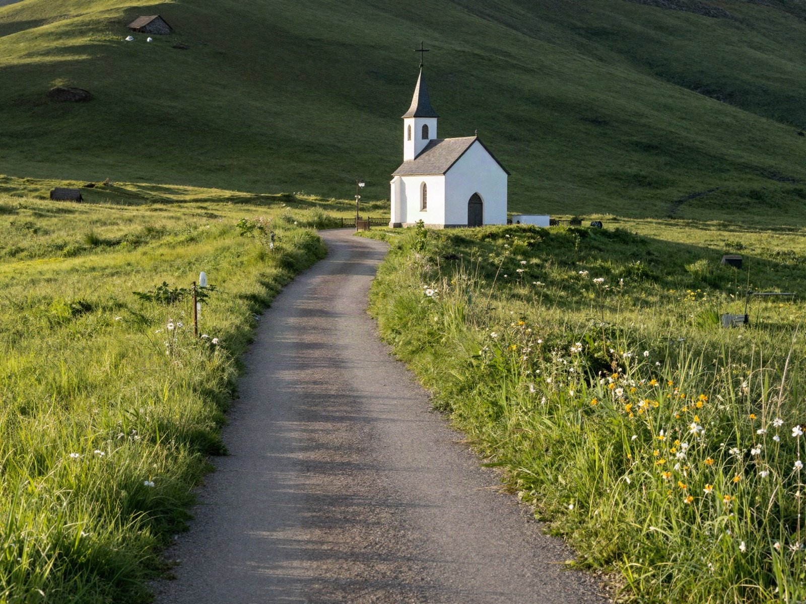Footpath through a meadow to a small white chapel
