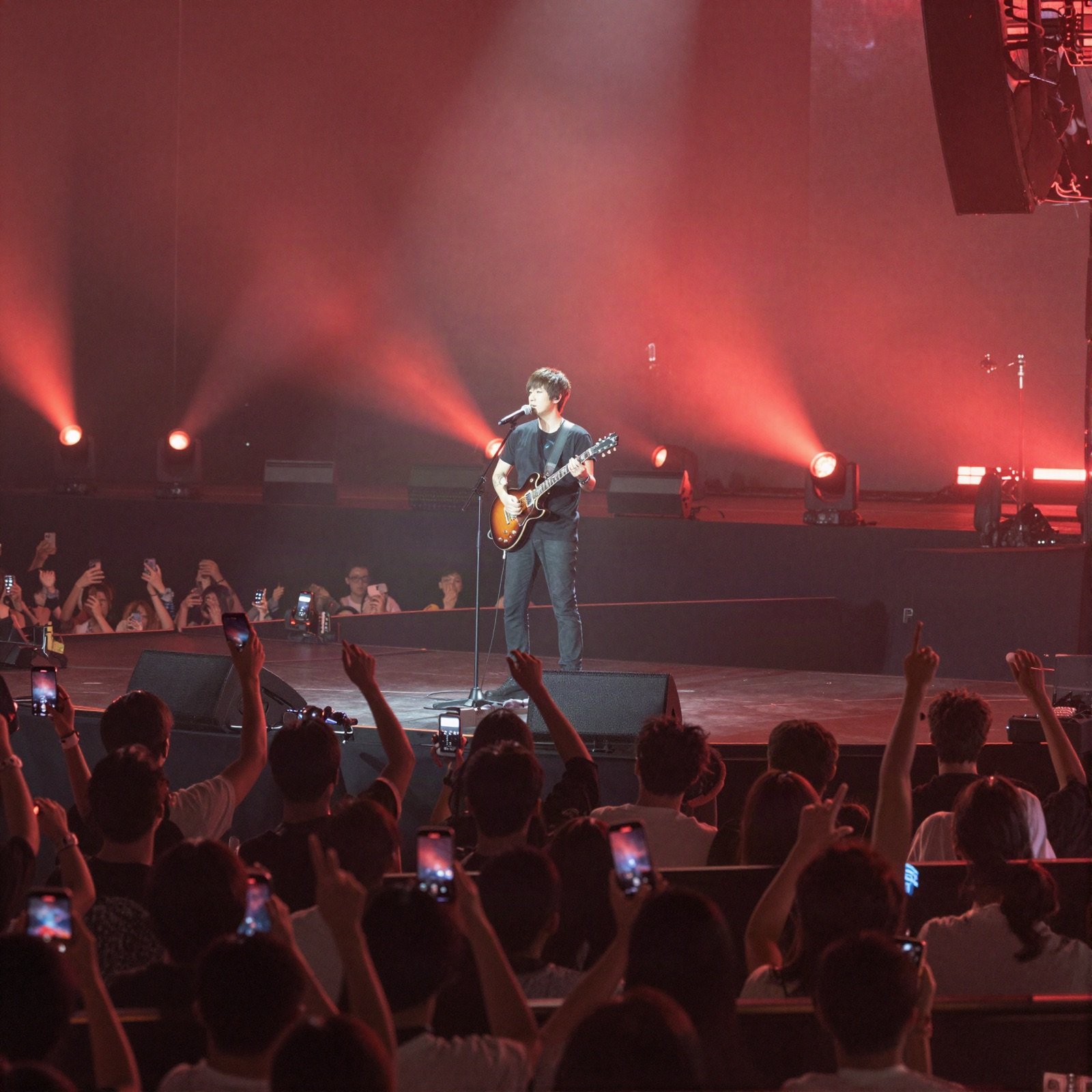 Guitarist singing on a big stage under red spotlights