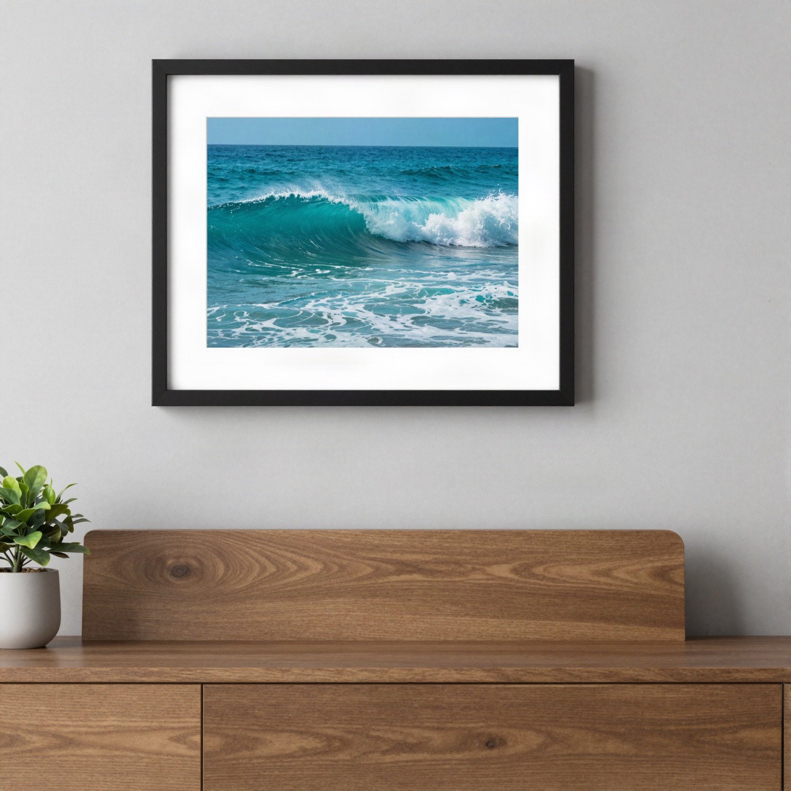 Framed print of a turquoise ocean wave above a wooden sideboard
