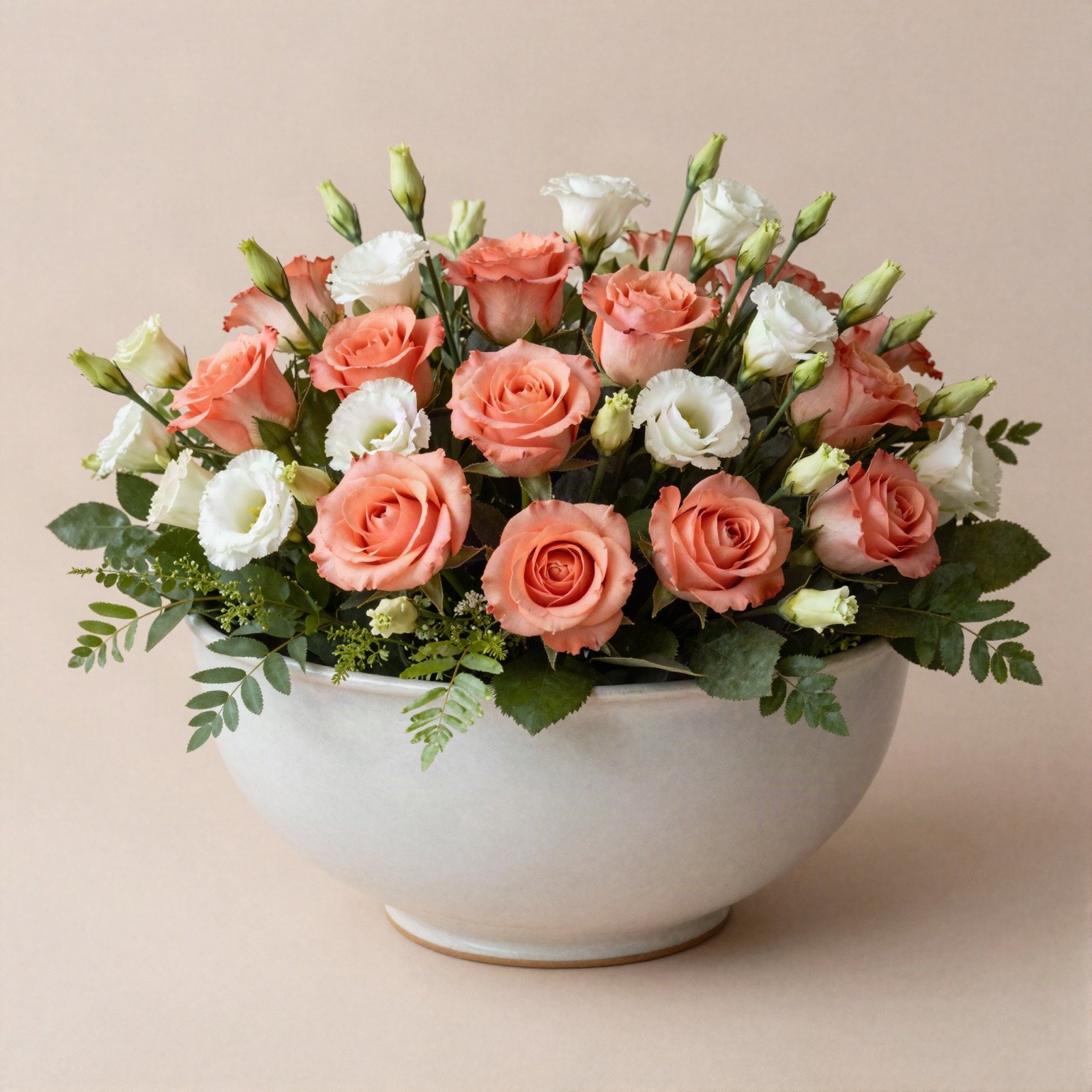Coral roses and white lisianthus arranged in a low ceramic bowl
