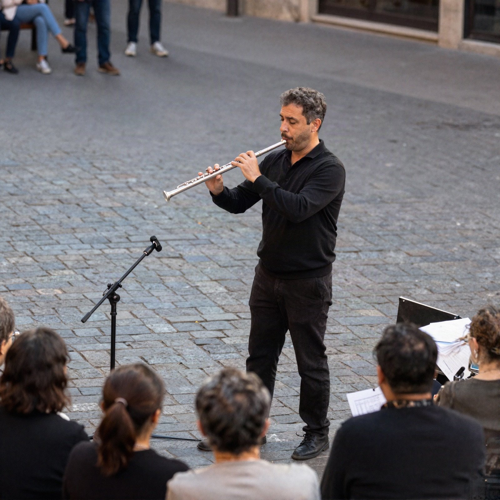 Flautist playing to a small crowd in a cobblestone square