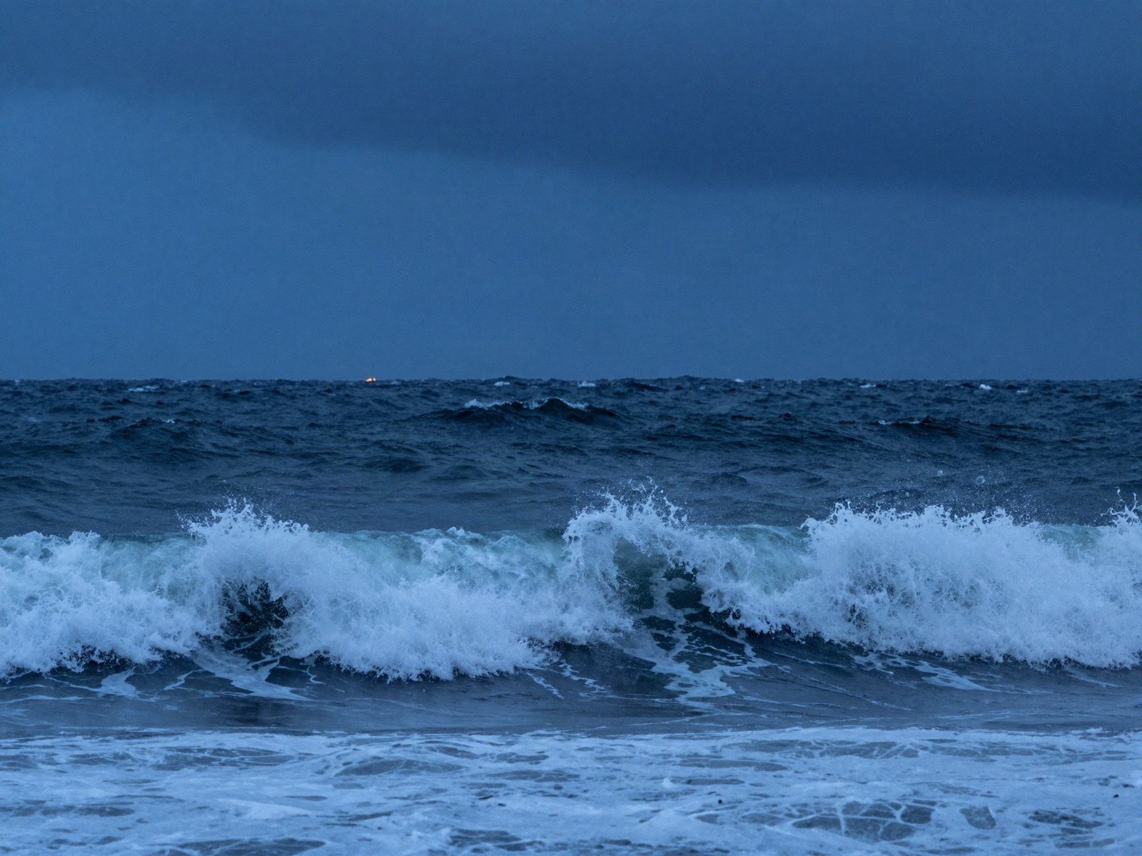 Stormy sea waves breaking under a dark blue sky