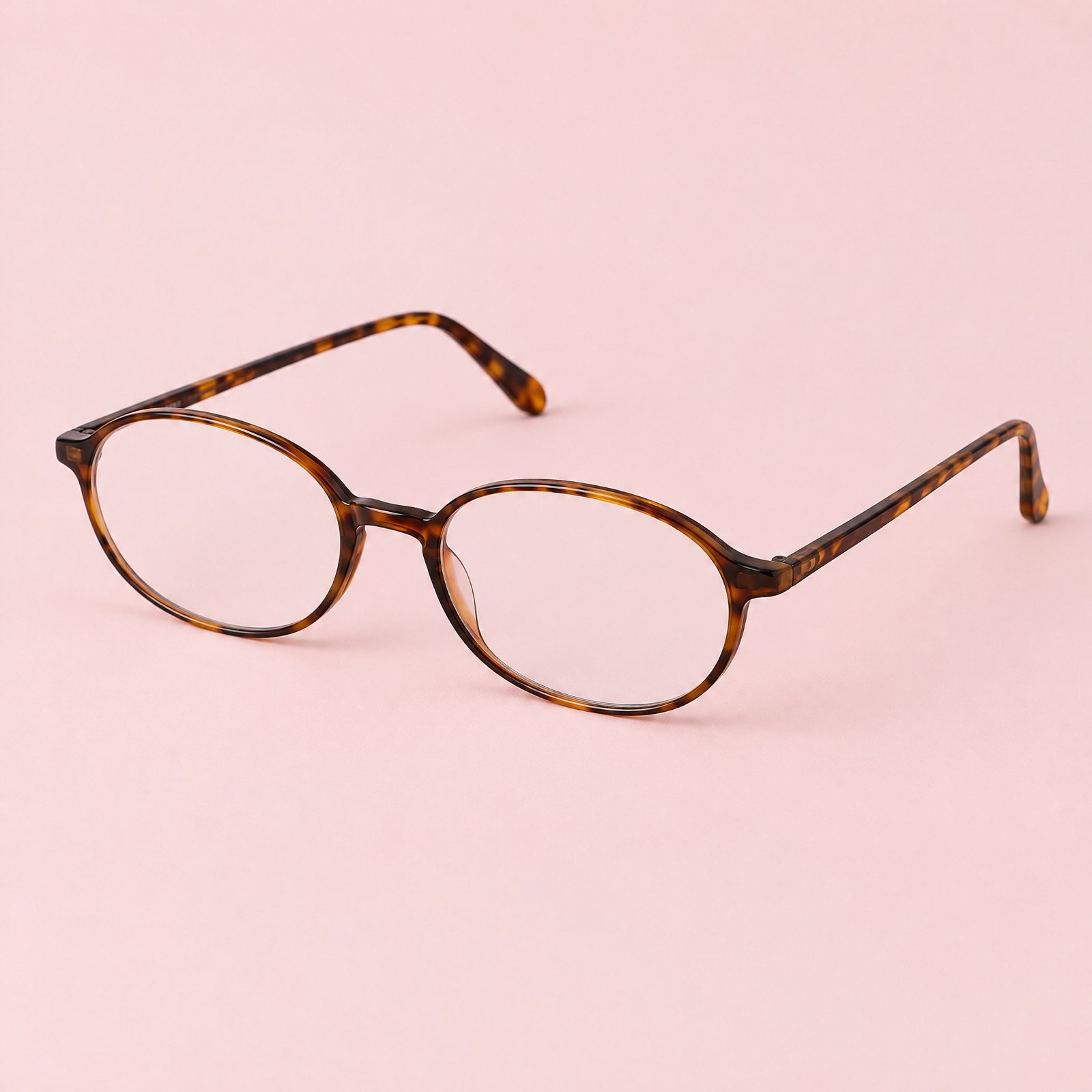 Oval tortoiseshell reading glasses on a blush pink background