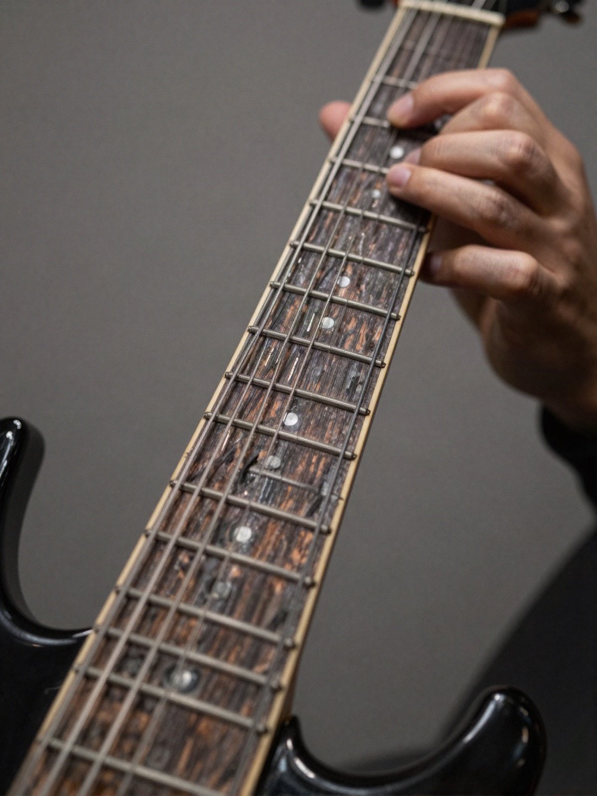 Close-up of fingers fretting a chord on an electric guitar neck