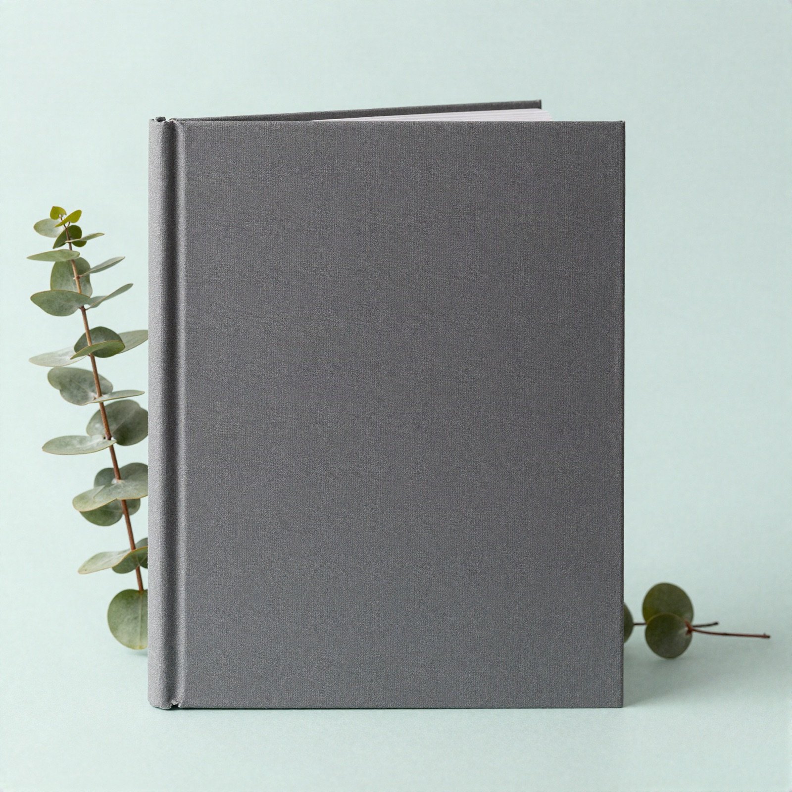 Charcoal grey hardcover book beside a sprig of eucalyptus