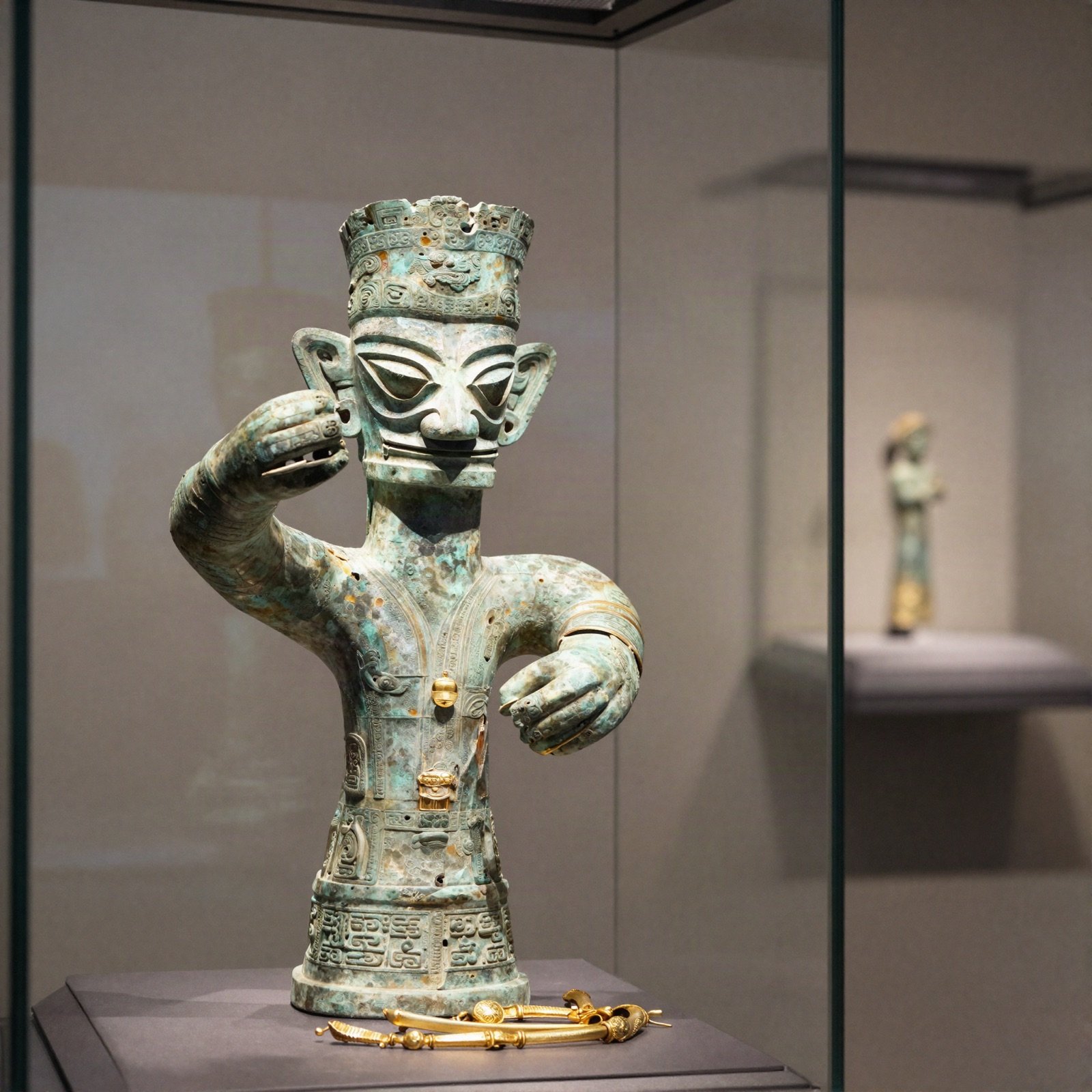 Ancient bronze figure and gold jewellery in a museum display case