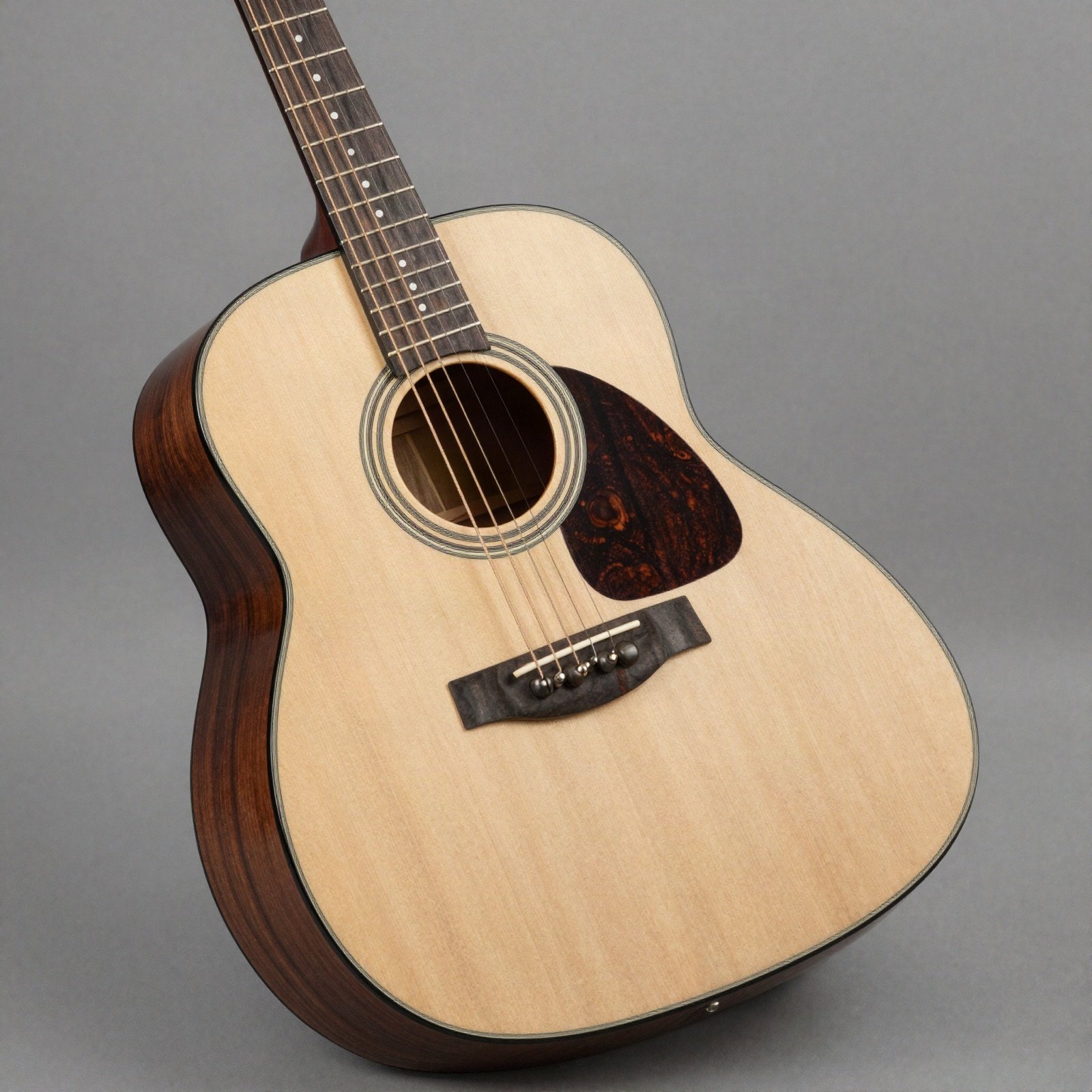 A rosewood and spruce acoustic guitar on a plain grey background