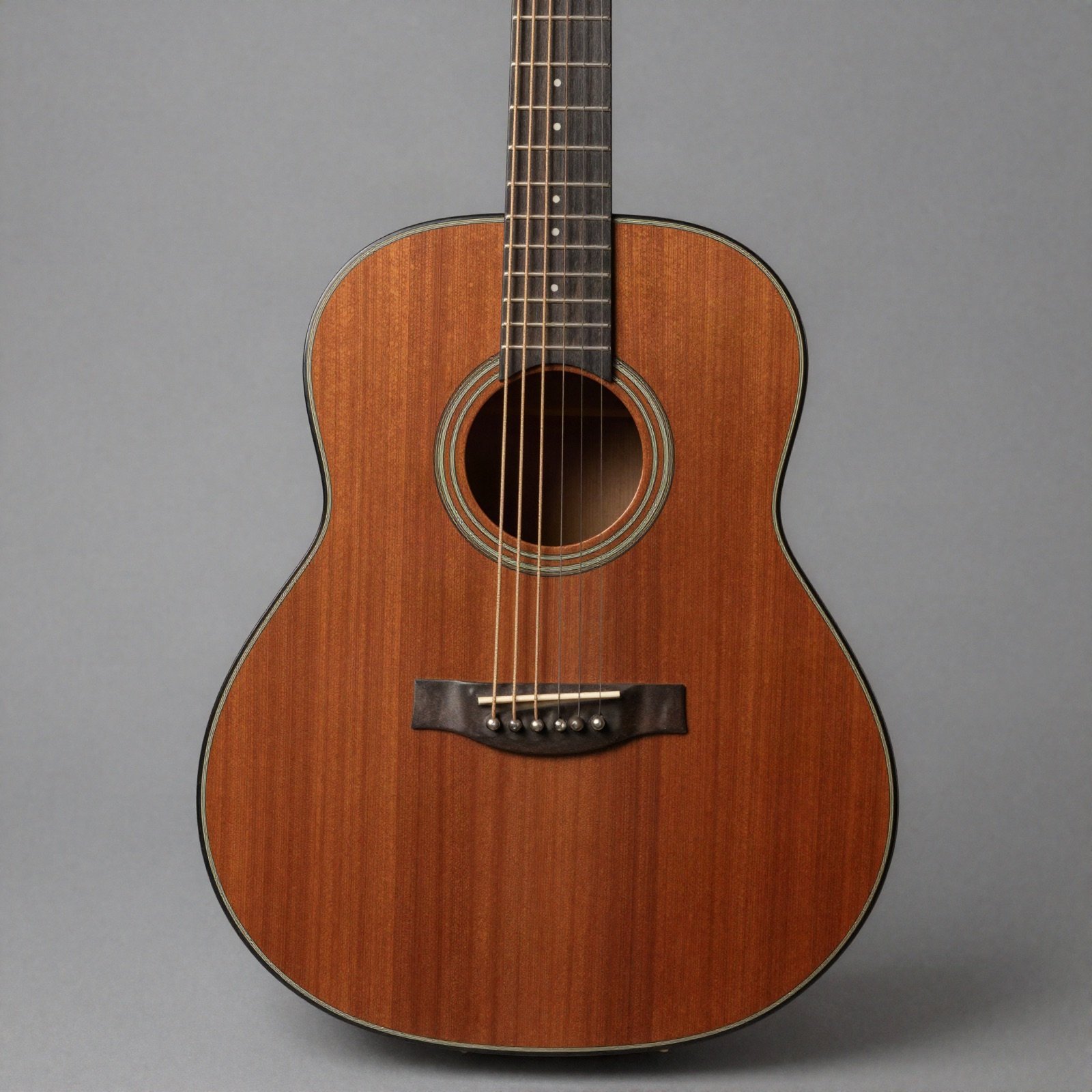 The body of an all-mahogany acoustic guitar on a plain grey background