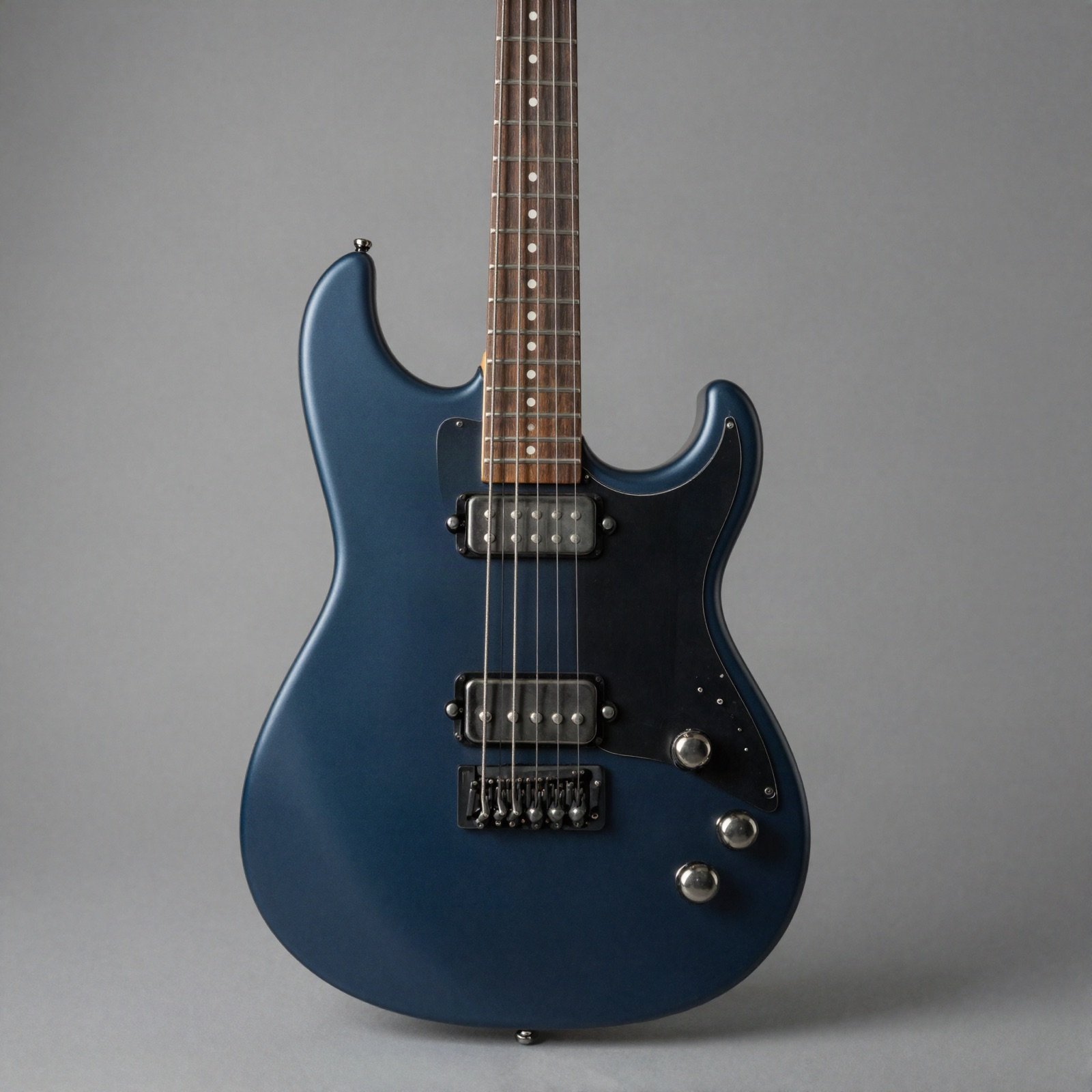 A matte midnight-blue electric guitar with two humbuckers on a plain grey background