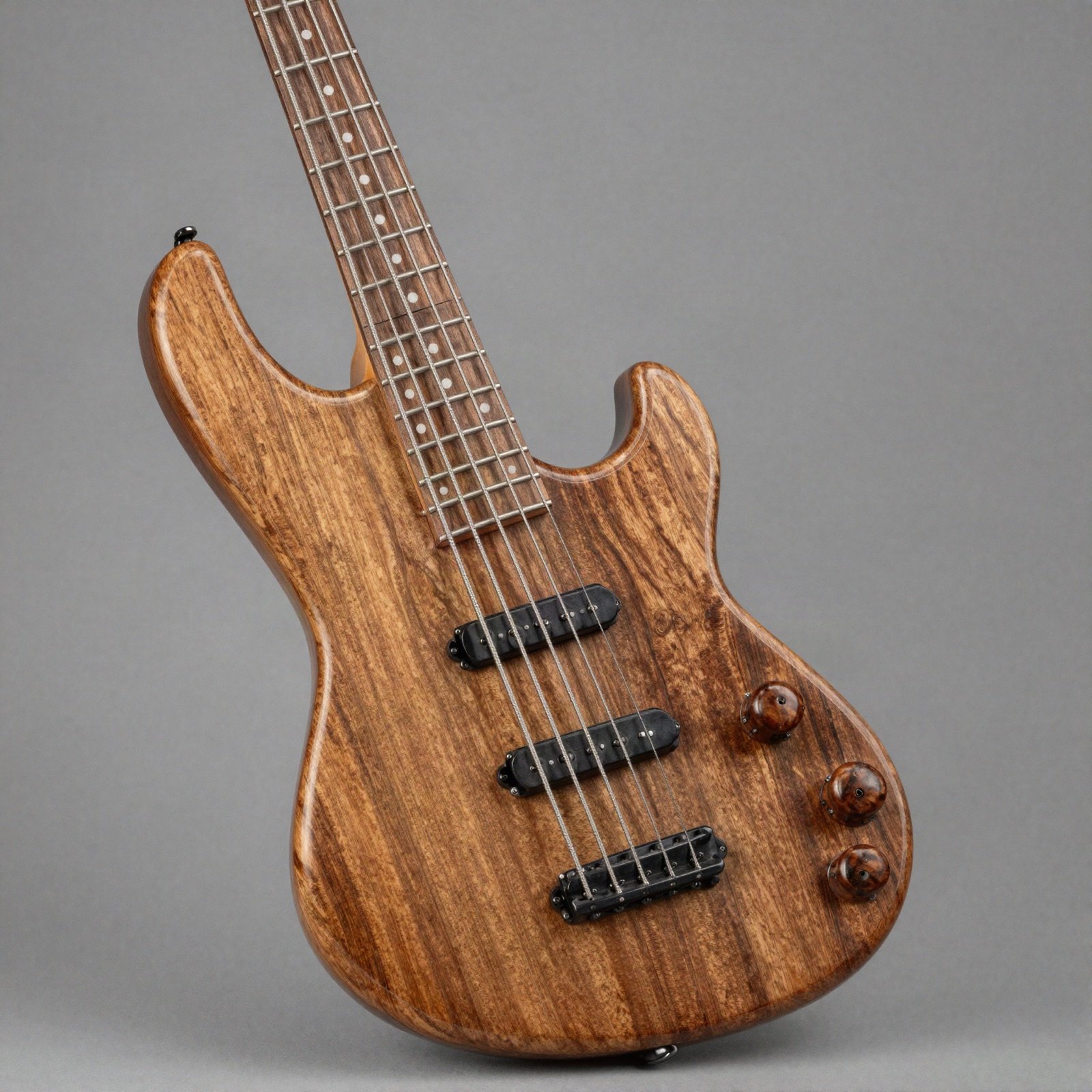 A four-string bass with a figured walnut body on a plain grey background