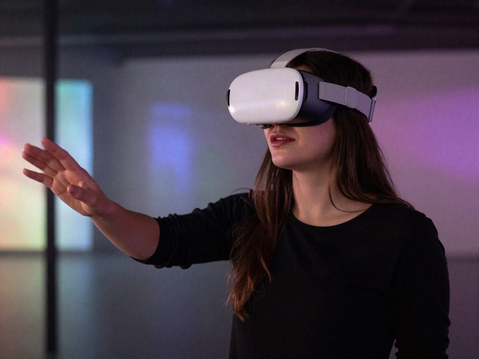 A woman wearing a virtual reality headset reaching out in a colourful dark gallery