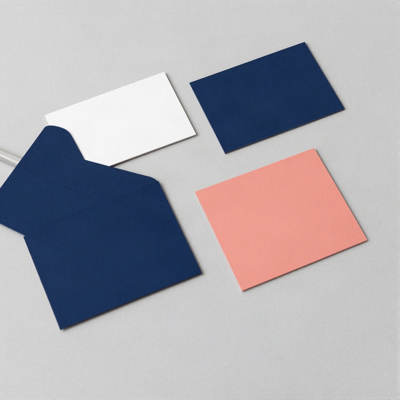 Navy, white and coral brand cards and an envelope on a grey desk