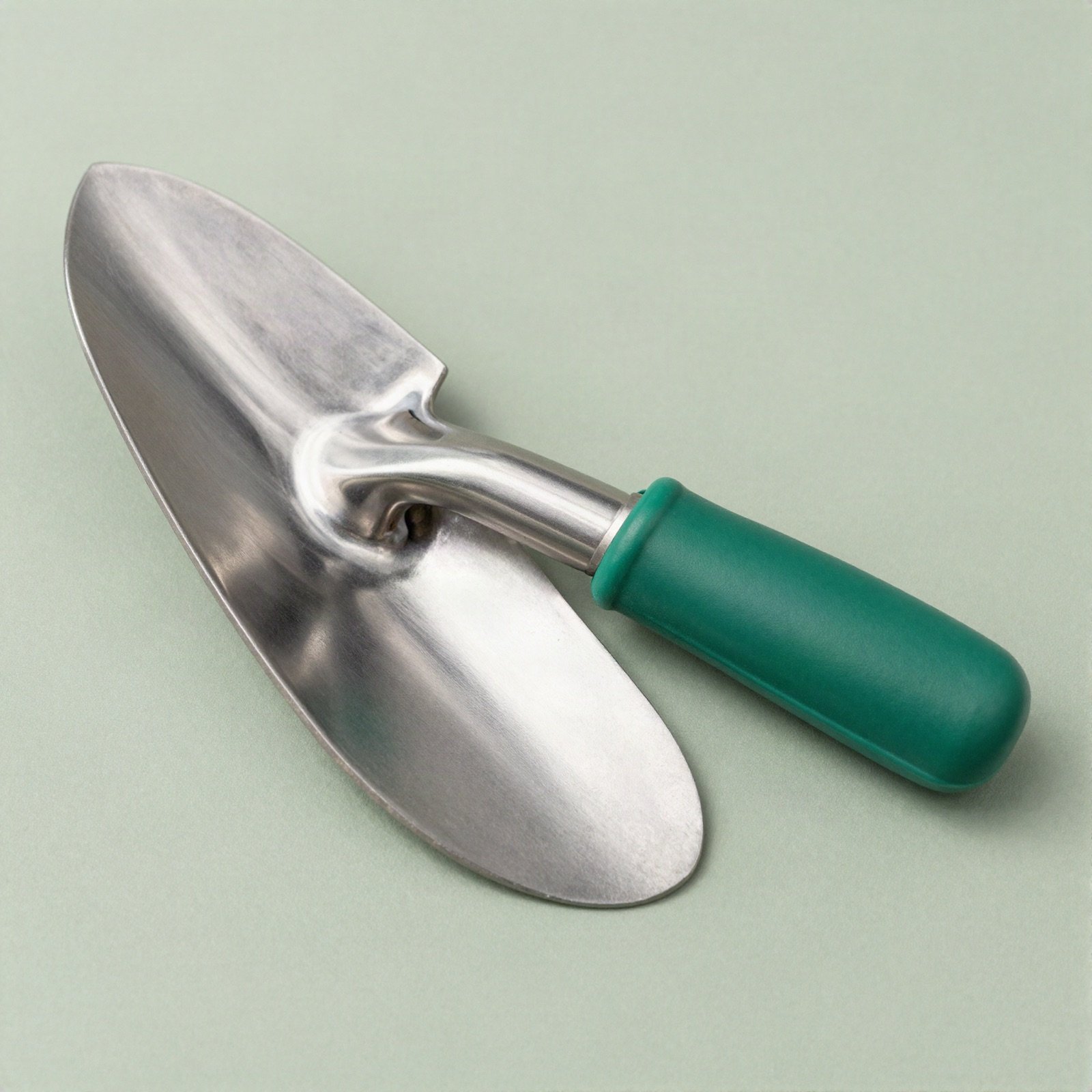 A steel hand trowel with a green handle
