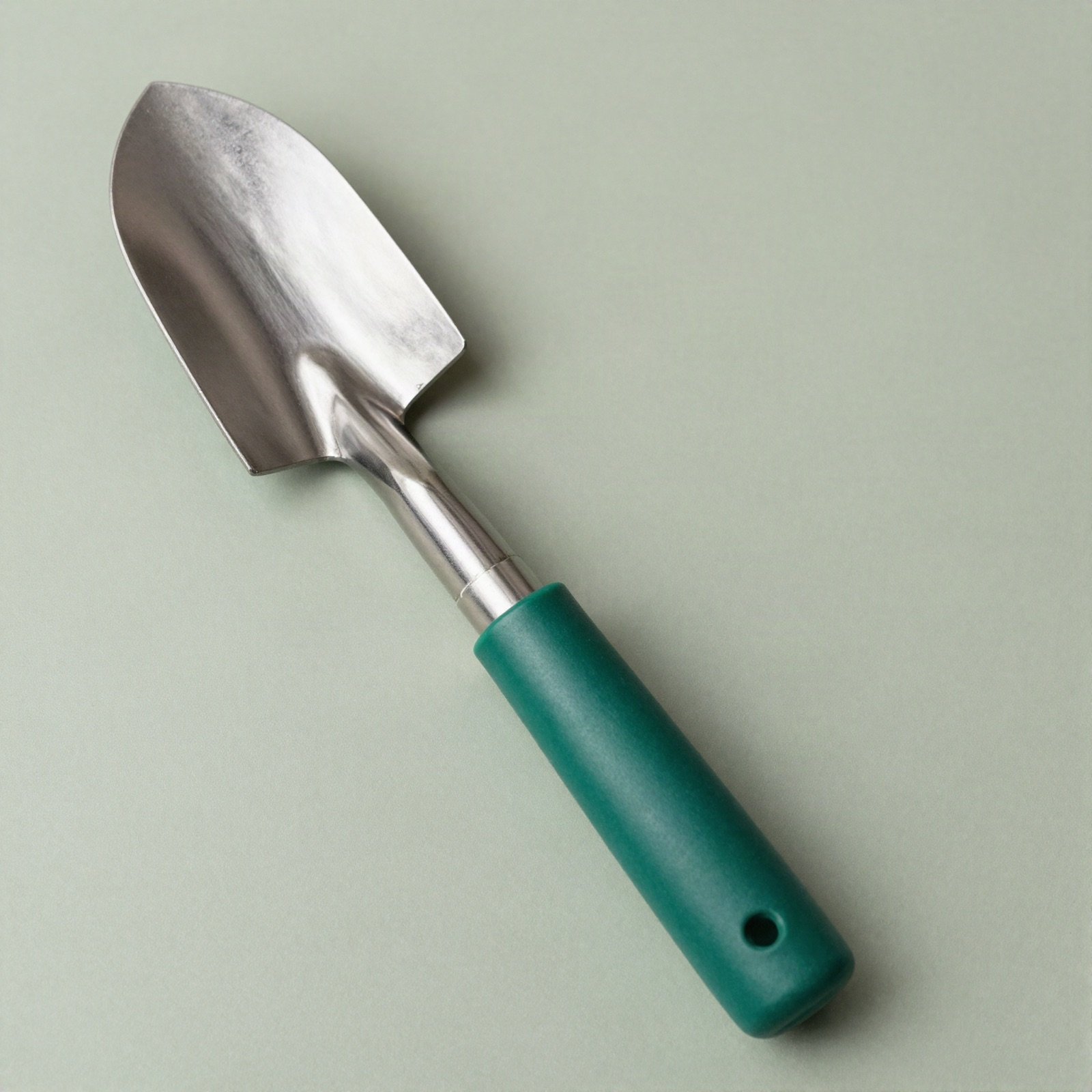 A narrow steel transplanter trowel with a green handle