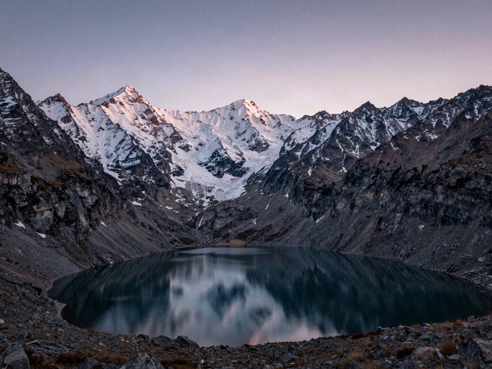 Snowy peaks reflected in a still alpine lake at dawn