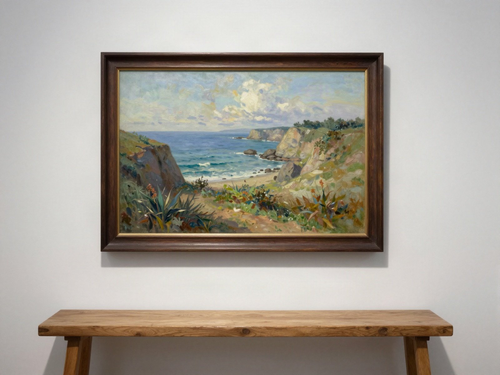 A framed coastal landscape painting above a wooden bench in a gallery