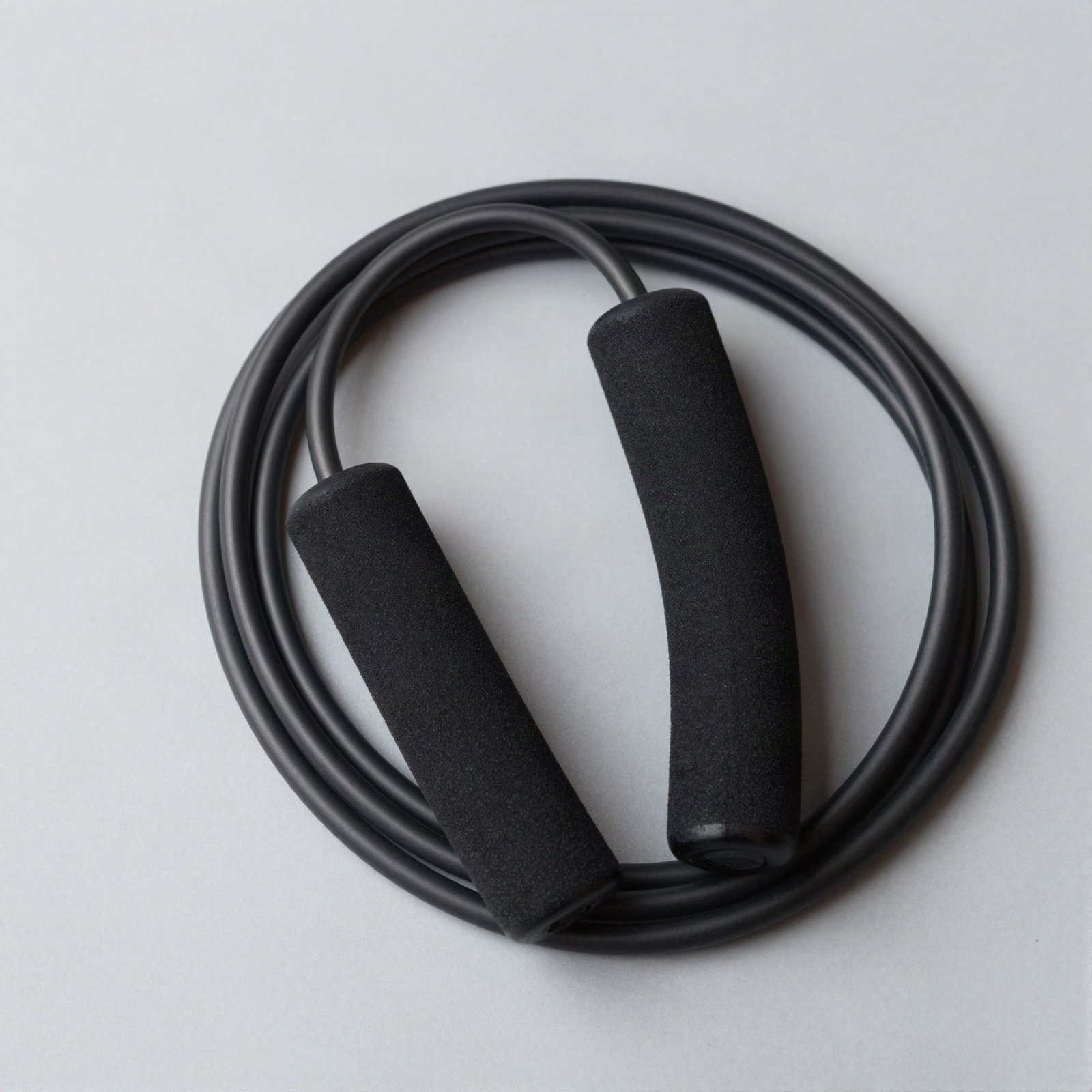 A coiled black jump rope with foam handles