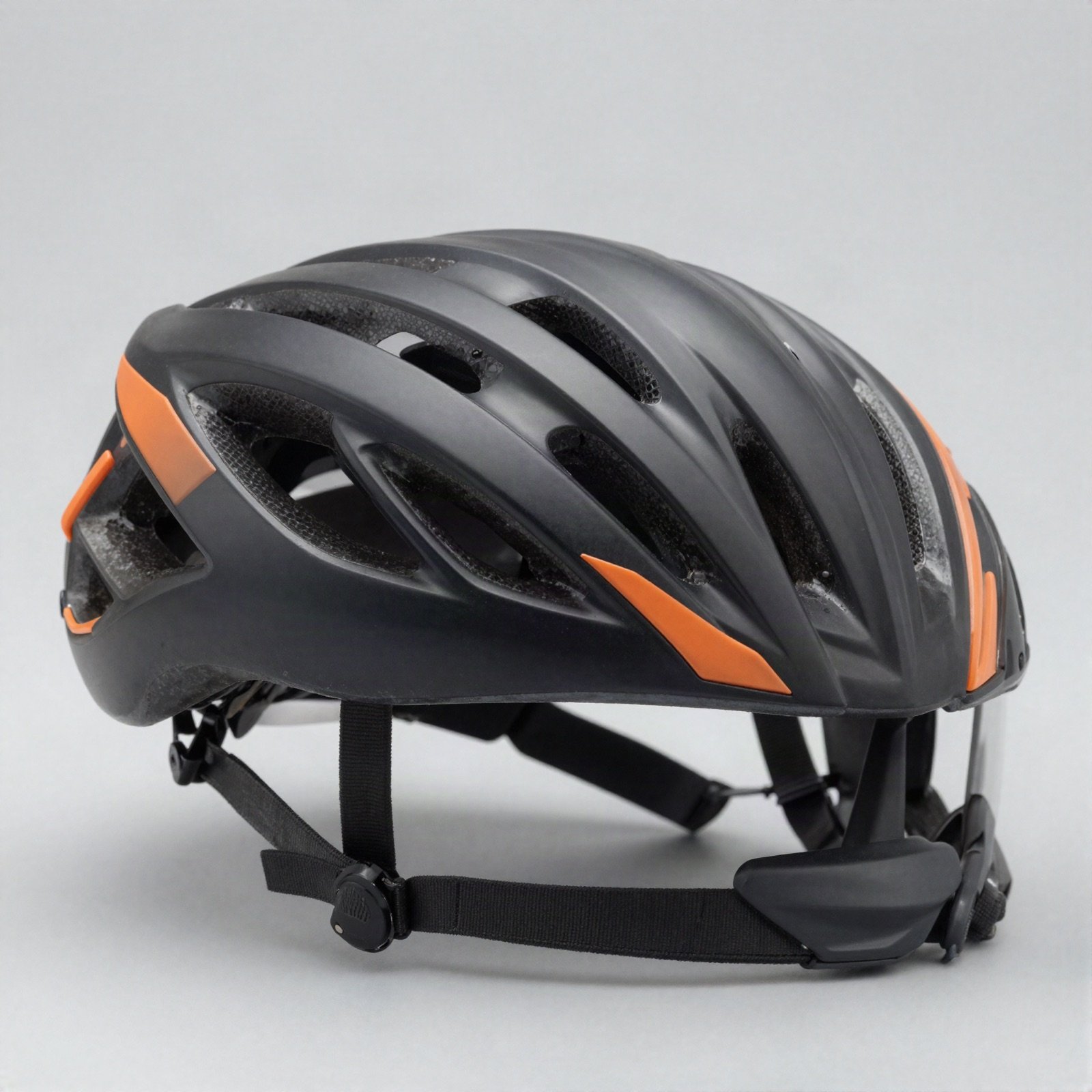 A vented black and orange cycling helmet with a visor