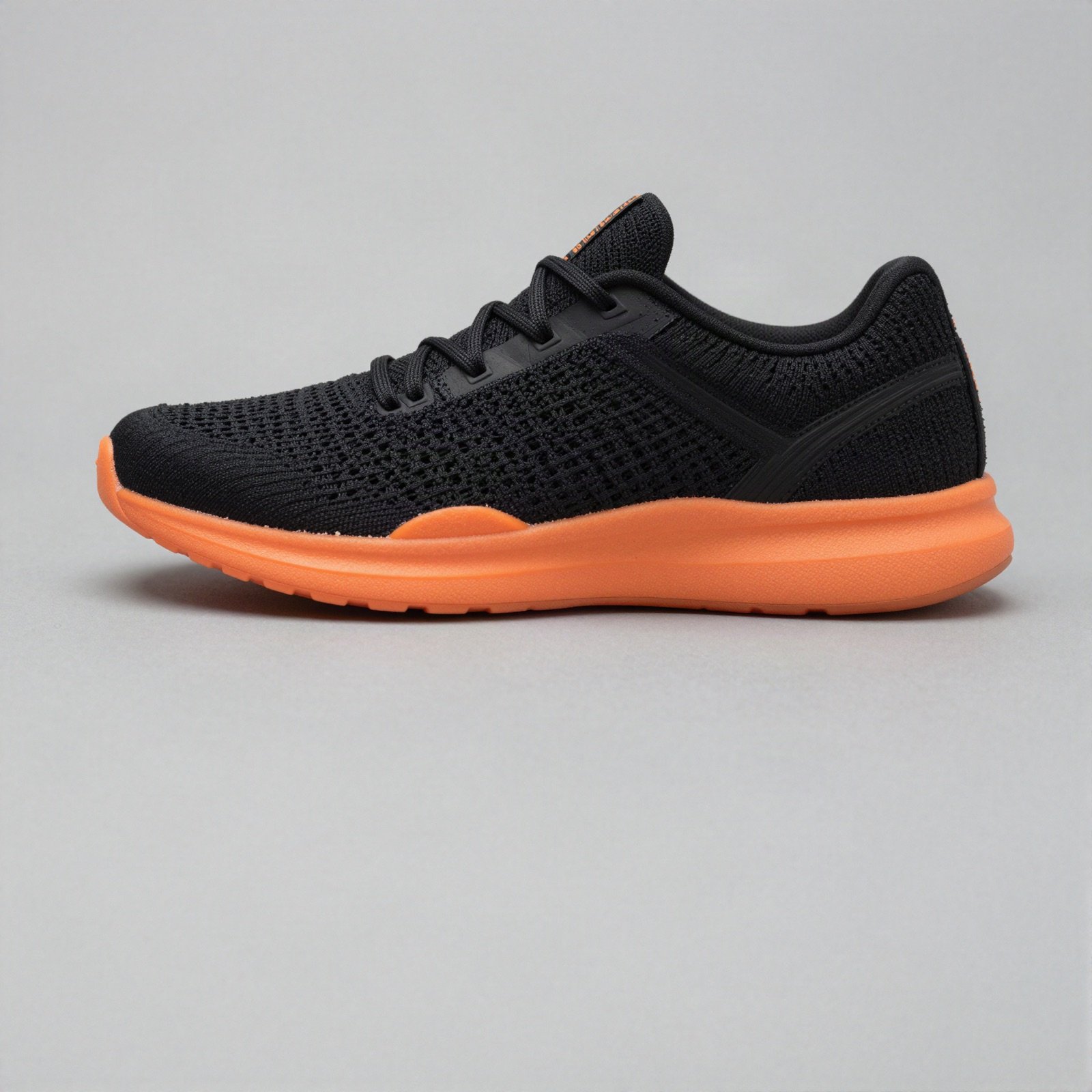 A black knit running shoe with a bright orange foam sole