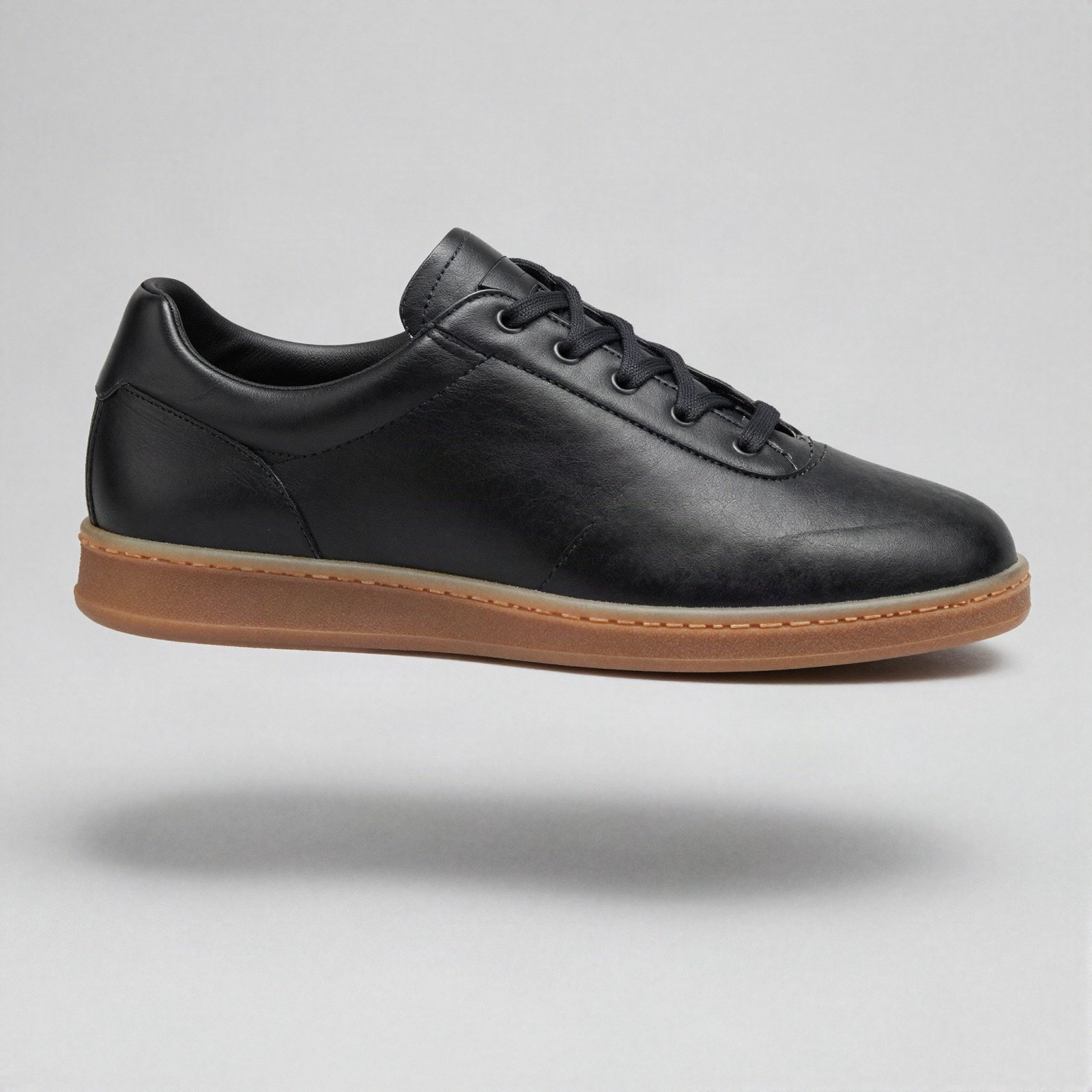 A plain black leather training shoe with a gum rubber sole